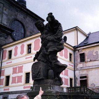 Man pointing at historic statue of knight on horse.