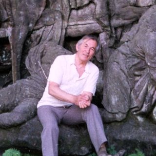 Man sitting beside ancient carved rock relief.