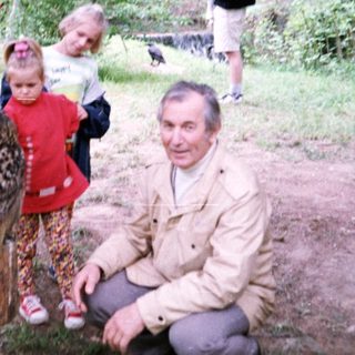 People interacting with a leopard-spotted animal in a forest setting.