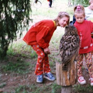 People interacting with a leopard-spotted animal in a forest setting.
