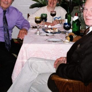 Four adults enjoying a meal and drinks indoors.