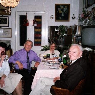 Four adults enjoying a meal and drinks indoors.