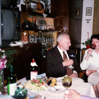 Celebratory gathering with elderly couple enjoying wine.