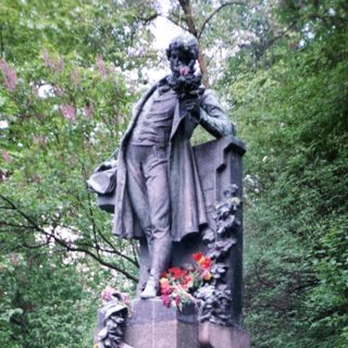 Man posing with floral wreath at historic monument.