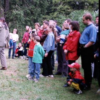 People observing a man feeding a large bird.