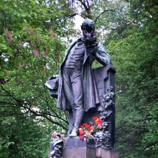 Statue honoring a historical figure with floral tributes.