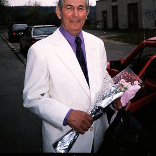 Man in white jacket holding wrapped gift bundle.