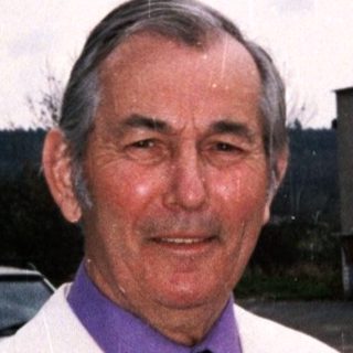 Man in white jacket holding wrapped gift bundle.