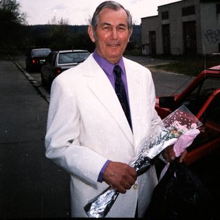 Man in white jacket holding wrapped gift bundle.