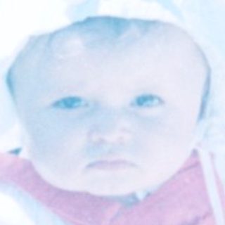 Baby in winter clothing seated in stroller outdoors.