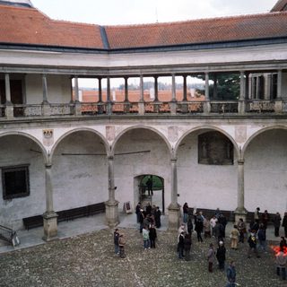 Historic courtyard with arched colonnades and people.