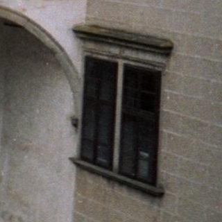 Historic courtyard with arched colonnades and people.
