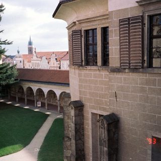 Historic courtyard with arched colonnade, old town spires.