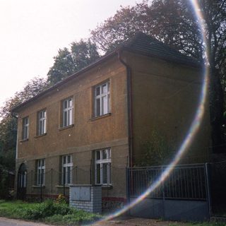 Two-story brick building surrounded by fence.
