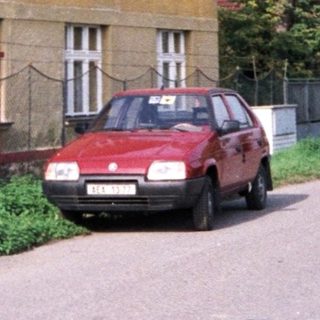 Rural street with yellow house, parked red car.