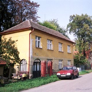 Rural street with yellow house, parked red car.
