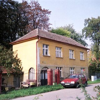 Yellow two-story house with red car parked outside.