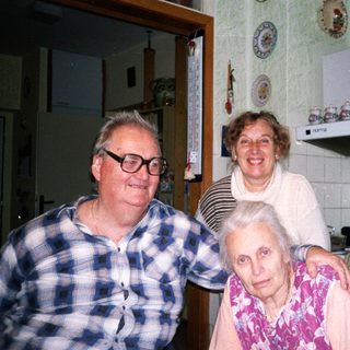 Three generations posing happily in a kitchen.