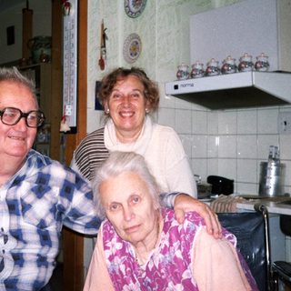 Three generations posing happily in a kitchen.