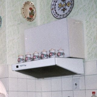 Three elderly people posing together in a vintage kitchen.