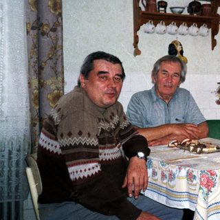 Three elderly people sitting together indoors at a table.