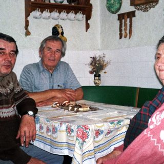Three elderly people sitting together indoors at a table.