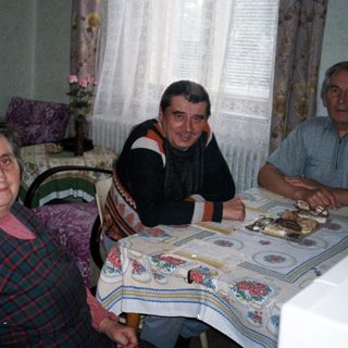 Family gathered around table with cake indoors.