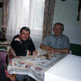 Family gathered around table with cake indoors.