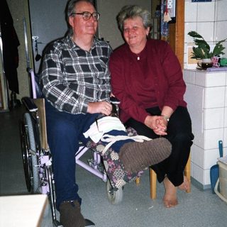 Two elderly individuals sitting together indoors.