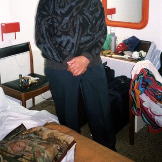 Man standing in a simple hotel room.