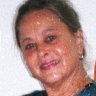 Woman posing in hotel room with luggage and clothes.