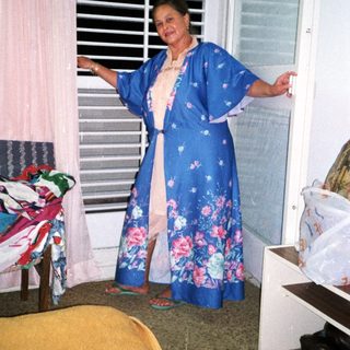 Woman wearing floral blue kimono by open window.