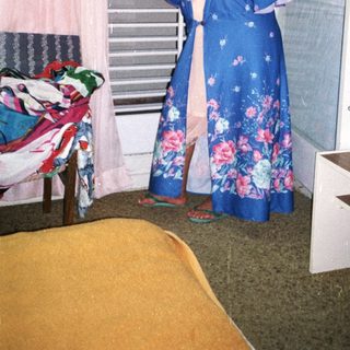 Woman wearing floral blue kimono by open window.