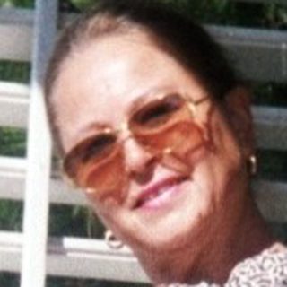 Woman standing outside in patterned jacket and cropped pants.