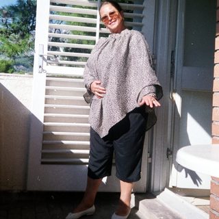 Woman standing outside in patterned jacket and cropped pants.