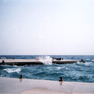 Boat launching off dock into rough sea.