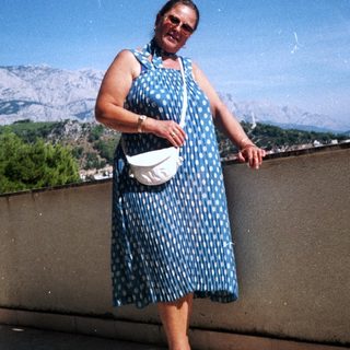 Woman in polka-dot dress posing outdoors near mountains.