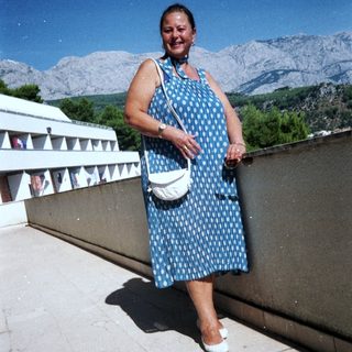 Woman smiling outdoors in mountain landscape.