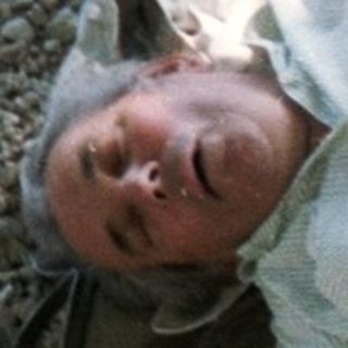 Person relaxing on camping mat near water.