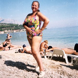 Woman posing on beach in colorful swimsuit.
