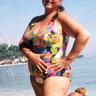 Woman posing on beach in colorful swimsuit.