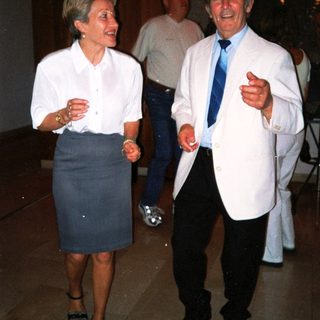 Two people laughing and conversing indoors at an event.