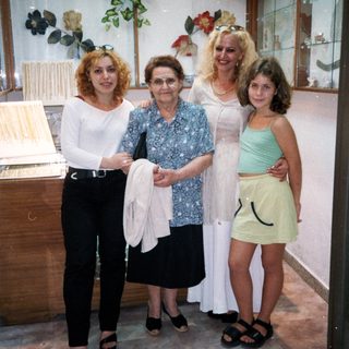 Four women posing together indoors near clothing displays.