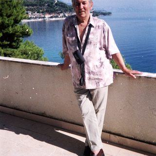 Man standing by seaside with scenic mountain view.