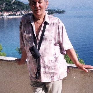 Man standing by seaside with scenic mountain view.