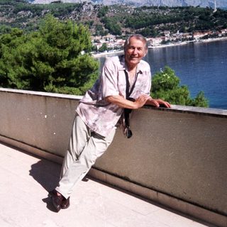 Man posing on rooftop overlooking coastal city.