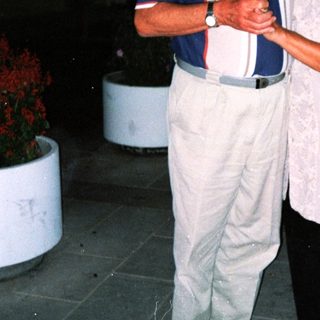 Two elderly people smiling together outdoors at night.