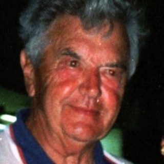 Two elderly people smiling together outdoors at night.