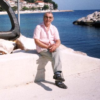 Man sitting by seaside with large anchor.