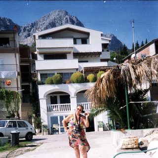 Woman using hosepipe in sunny residential area.